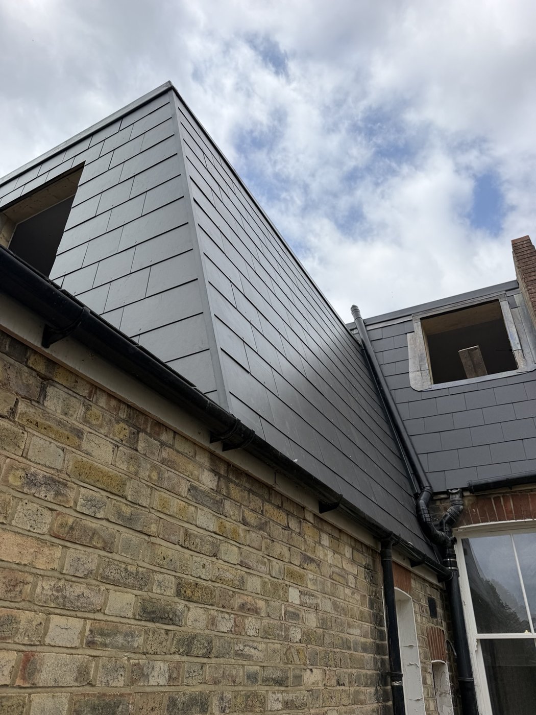 Slate-style roof addition with unfinished openings and scaffolding