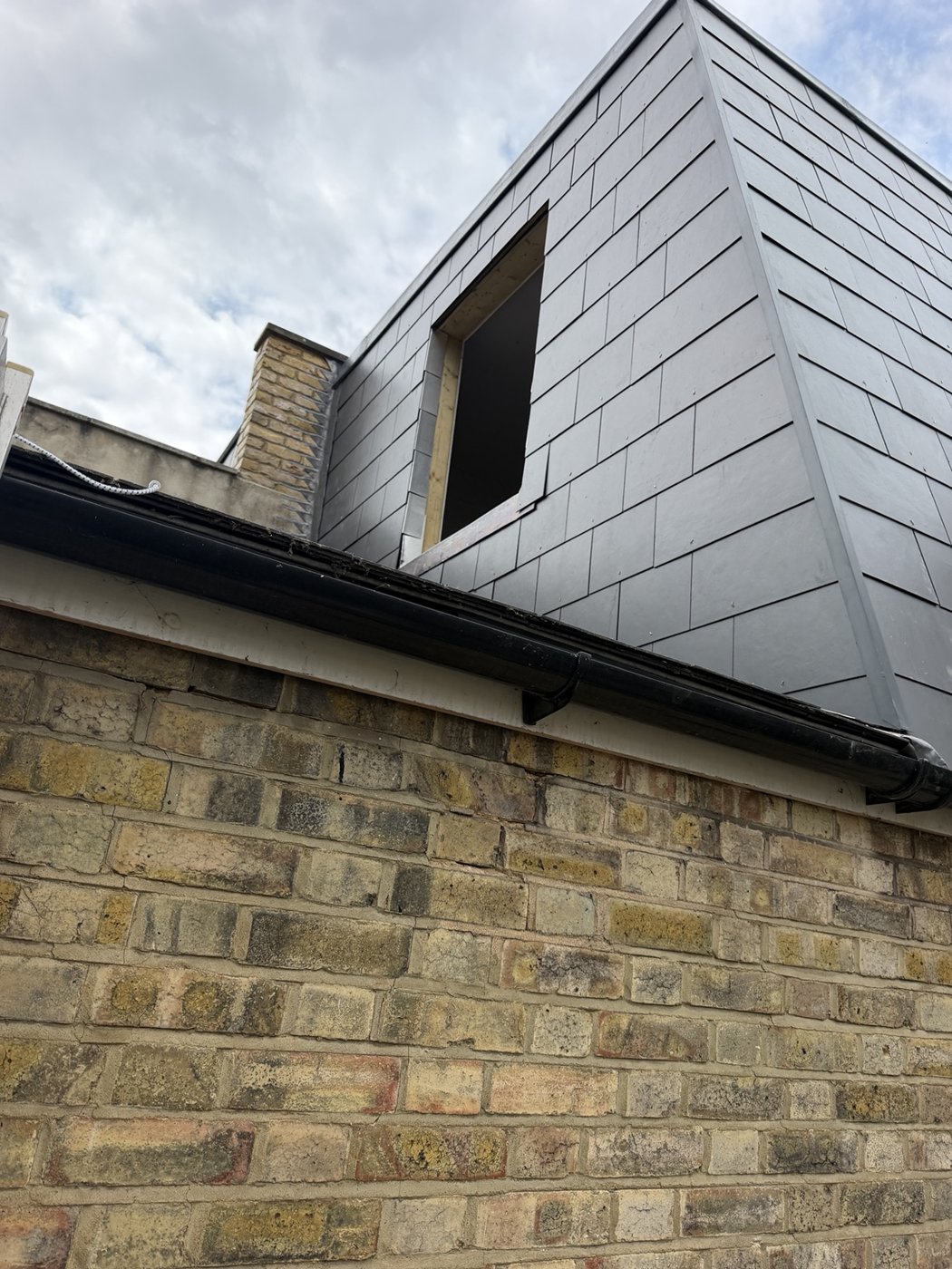 Close view of slate-style roof and wall cladding around an unfinished opening